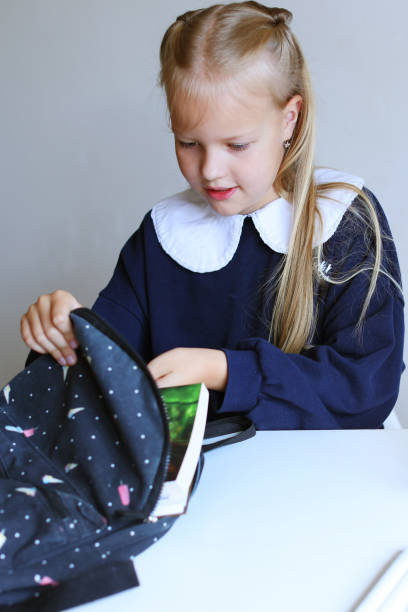 istock child put books and notes into backpack. School supplies.Back to school concept. School girl prepare staff for education. Kid prepare for studies. 1574448913