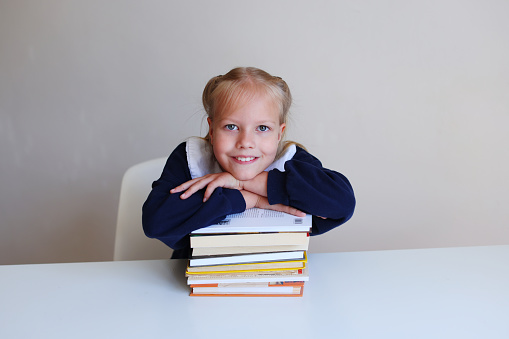 a schoolgirl with a book leaned her hand on a stack of textbooks.