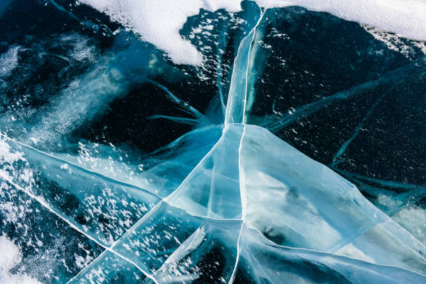 istock Transparent blue ice with cracks on Baikal lake in winter. 1574456057