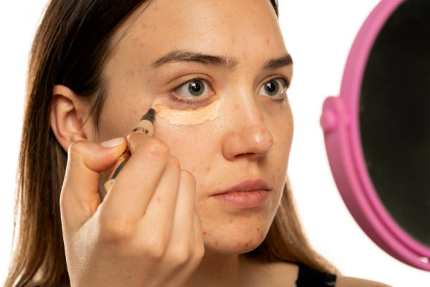 istock Young women applying concealer under her eyes and face 1574474564