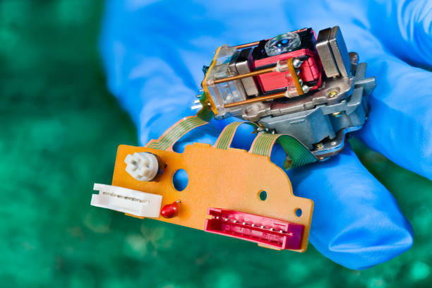 istock Closeup of optical pickup head with lens, coil springs, wire winding and connectors or resistor trimmer on flex cables 1574498992