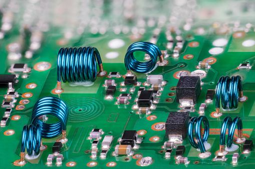 Closeup a planar spiral coil and electronic components in PCB surface copper layer and bokeh in a background