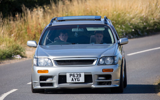 Turvey, Beds, UK - July 16th 2022. Silver 1997 Nissan Stagea  car driving on an English country road