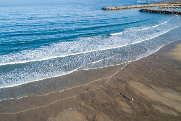 istock Aerial zenith view of a beach with two people walking on it 1574552349
