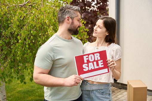 Loving man and woman with sign board looking at each other while standing in garden