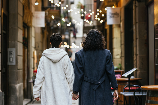 Couple of men walking away down an alley in the city holding hands, on their way to have dinner together.