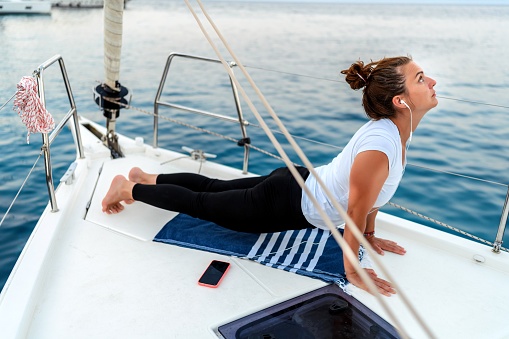 Woman relaxing and meditating on the prow of a boat on the sea