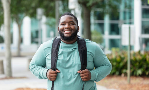 istock Young black man carrying backpack outside building 1574637238