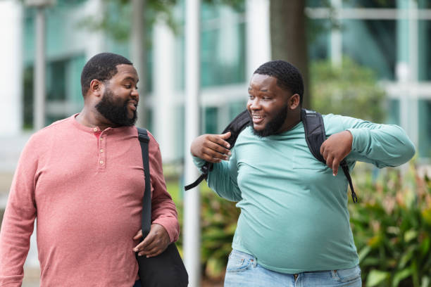 istock Two heavyset black men walking in city, conversing 1574637494