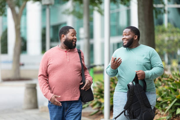 Two heavyset black men walking in city, conversing