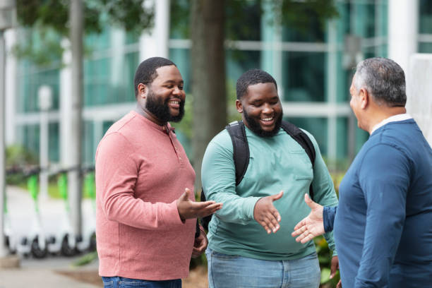 Three heavyset multiracial men meet, shake hands outdoors