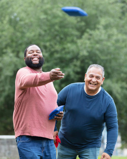 istock Two heavyset multiracial men playing bean bag toss 1574637830