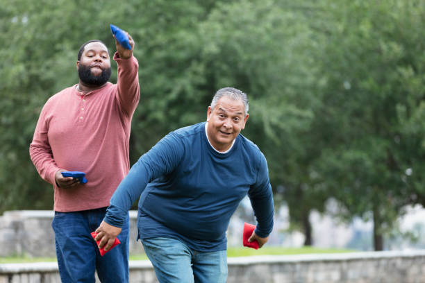 Two heavyset multiracial men playing bean bag toss stock photo
