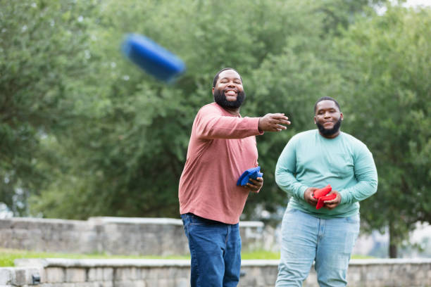 istock Two heavyset black men playing bean bag toss at the park 1574637849