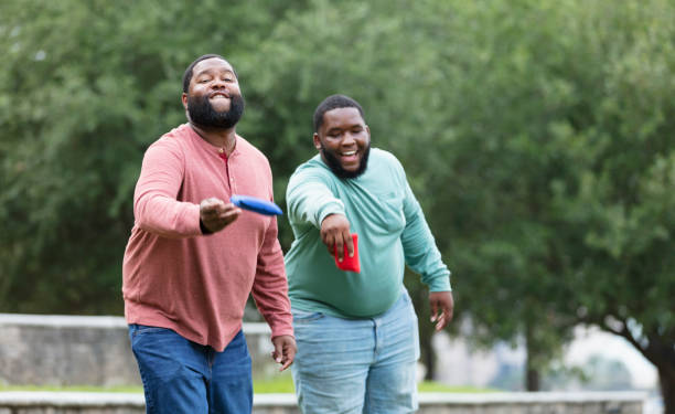 istock Two heavyset black men playing bean bag toss at the park 1574638359