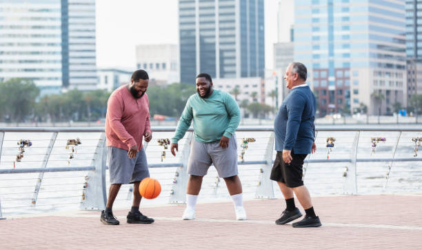 istock Three stout men playing with basketball on city waterfront 1574638383