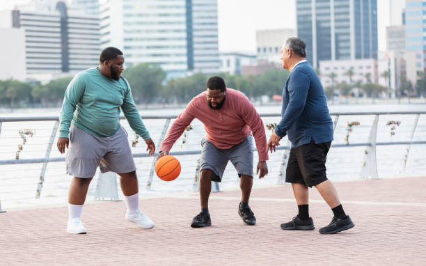 istock Three stout men playing with basketball on city waterfront 1574638394