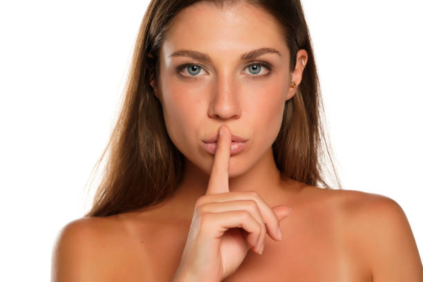 istock Young woman with finger on her lips 1574652707