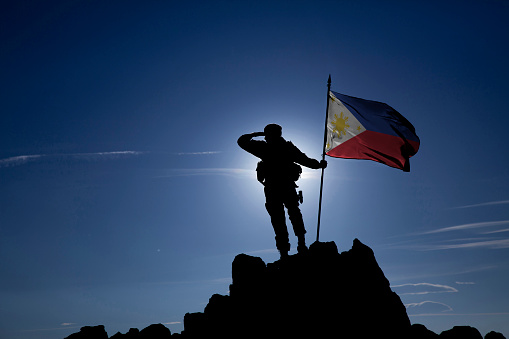 Soldier on top of the mountain with the Philippine flag