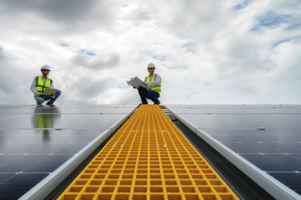 istock Young Engineers and Specialist Technicians Discuss and Check Quality of Installing Solar Photovoltaic Panels and Use App Technology Checking Accumulated power generation from Solar Panel on Laptop. 1574676527