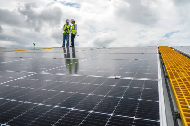 istock Young Engineers and Specialist Technicians  Discuss and Check Quality of Installing Solar Photovoltaic Panels and Use App Technology Checking Accumulated power generation from Solar Panel on Tablet. 1574676534