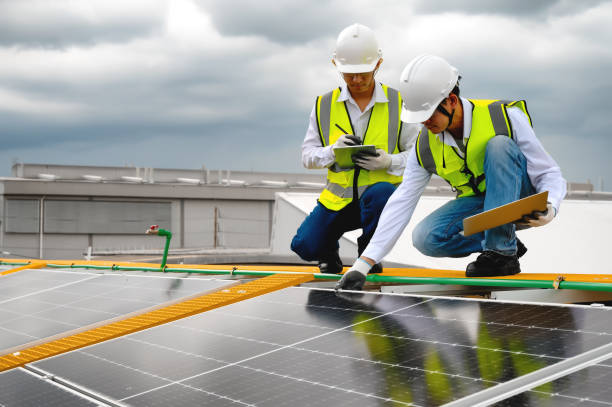 istock Young Engineers and Technicians Discuss and Check Quality of Installing Solar Photovoltaic Panels and Use App Technology Checking Accumulated power generation from Solar Panel on Tablet and Laptop. 1574676554