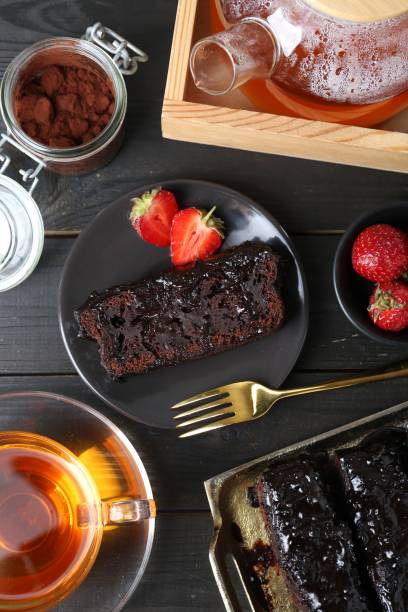 istock Tasty chocolate sponge cake served on black wooden table, flat lay 1574714549