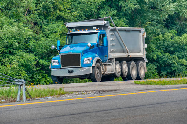 Horizontal shot of a blue dump truck on a divided highway.