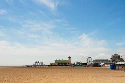 Great Yarmouth, Norfolk. The beach, Wellington Pier and Winter Gardens, with cranes at the Outer Harbour development in the background.