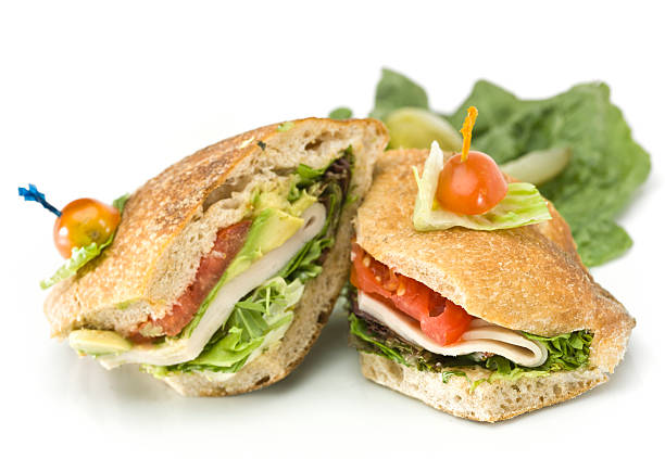 Smoked ham and salad sandwich with cheese made with brown bread. Sandwich on a wooden bread board. 