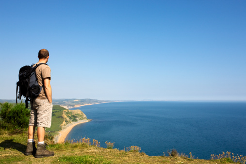 Man standing at the edge of a cliff looking out to sea