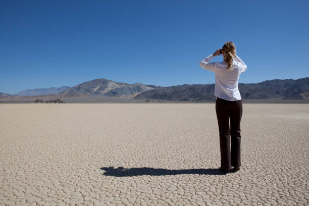 istock Woman looking through binoculars on a dry lake bed 157473711