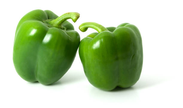 Two green bell peppers isolated on a plain white background