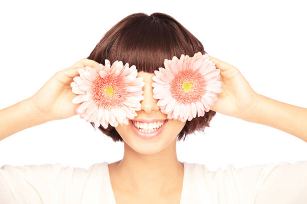 笑顔の若い女性は目を覆う花 - wearing flowers ストックフォトと画像
