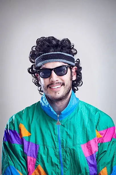 A cool, funky young adult from the late 20th century complete with mullet, fluorescent track suit, and tinted sun glasses.  Vertical with copy space.