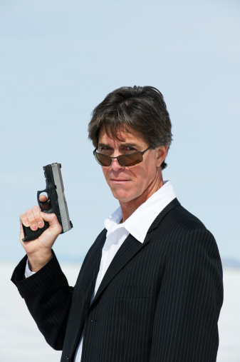 Man holding a gun looking down his sunglasses