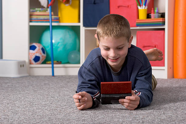 Boy Playing Video Game On Playroom Floor, Smiling, Horizontal stock photo