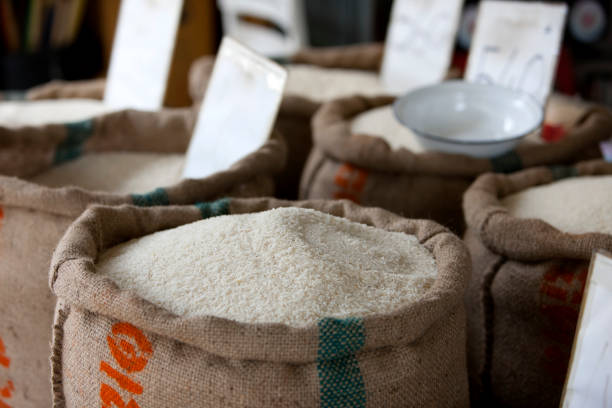 Thai rice for sale in a market. Thai rice in hemp sacks for sale in a market. Shallow depth of field, focus on the rice in the foreground sack.  rice sack stock pictures, royalty-free photos & images