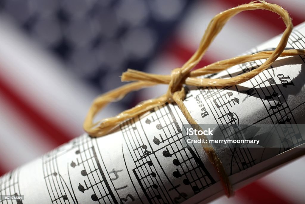 American Music XXXL photo of a rolled up peice of sheet music with dramatic lighting in front of a blurred American Flag Music Stock Photo