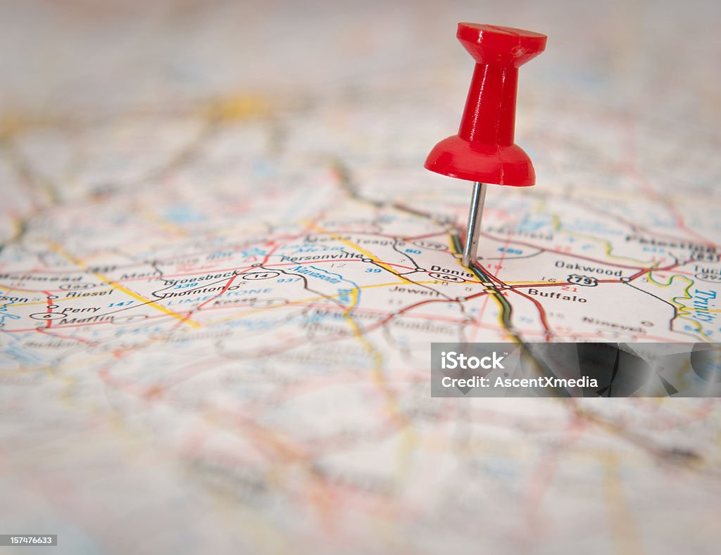 Close-up of a push pin stuck in a map Red thumb tack marking a spot on a map Thumbtack Stock Photo