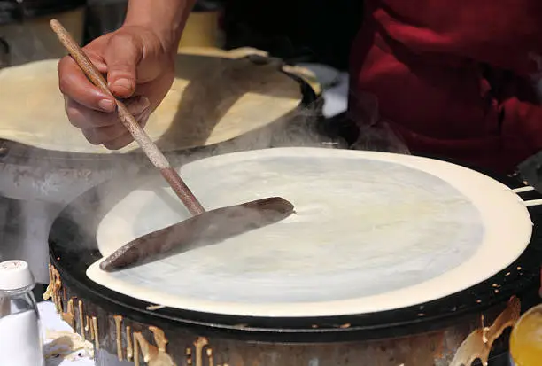 Making crepes on a traditional round griddle. This is a common inexpensive snack sold everywhere in France. French fast food! Sweet crepes make a nice desert. Other options include ham and cheese. They're all delicious!