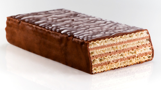 A dark chocolate wafer photographed on white reflective surface