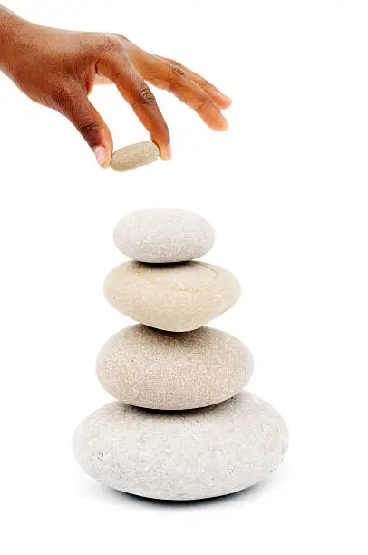 Photo of hand stacking stones on a stone tower