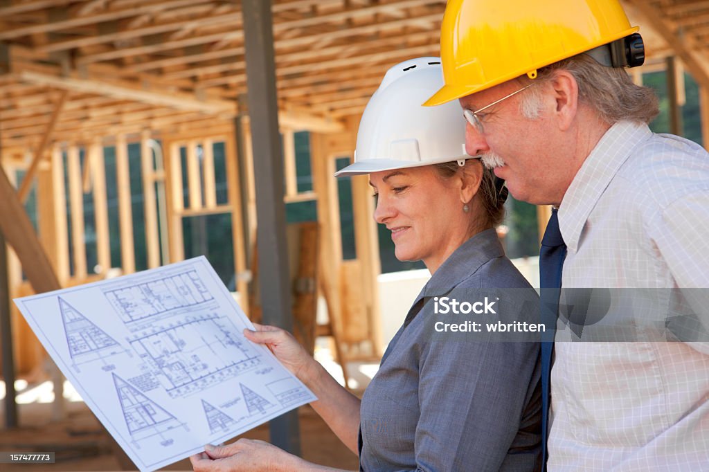 Profesional de hombre y mujer en el sitio de construcción (XXL - Foto de stock de Accesorio de cabeza libre de derechos