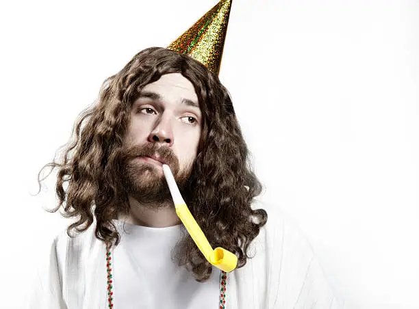 Happy Birthday.  Long-haired man dressed in a robe wearing a party hat and party horn