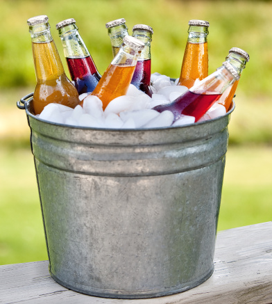 a metal bucket filled with ice and cold colorful bottles of soda