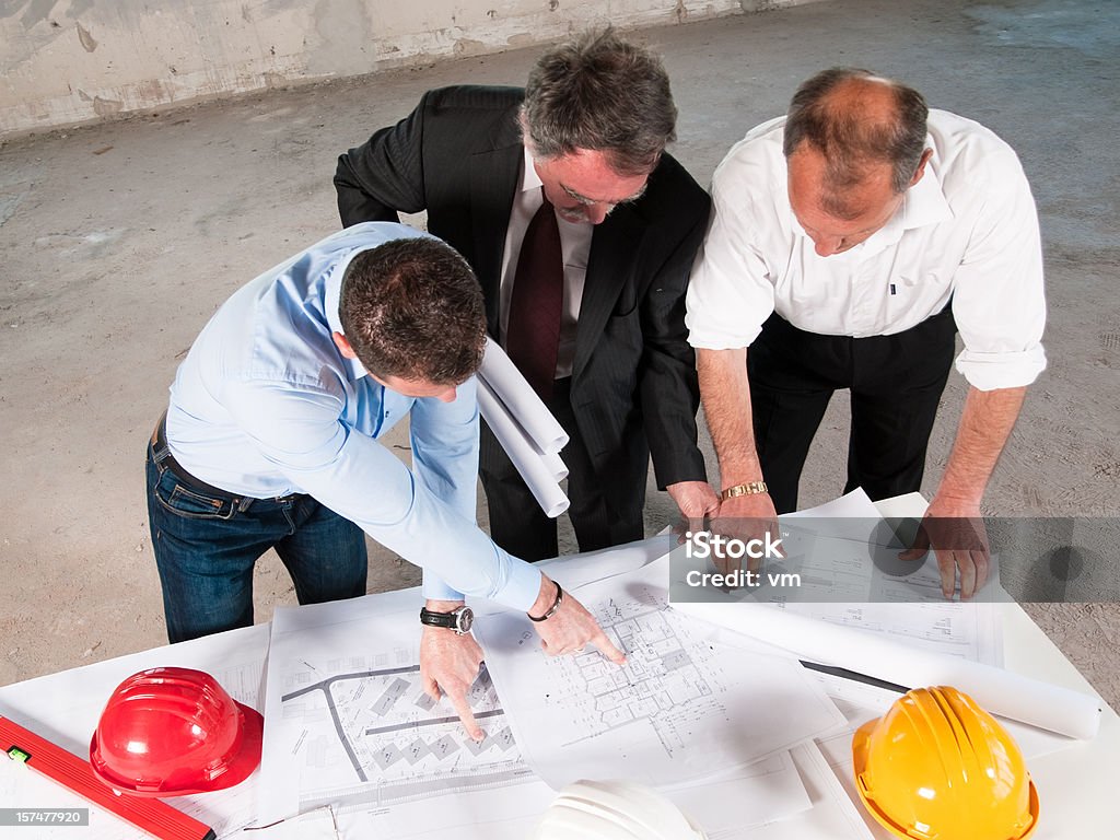 Gruppo di uomini d'affari esaminando piantine insieme su luogo di costruzione - Foto stock royalty-free di Adulto