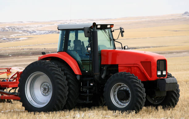 A new red tractor on the prairie in winter. Agricultural machinery with cultivator on field in late fall after harvest. Image location is near Calgary, Alberta. Additional themes could be tires, rubber, farming, cultivating, machinery, industrial equipment, growing, and rural life.  