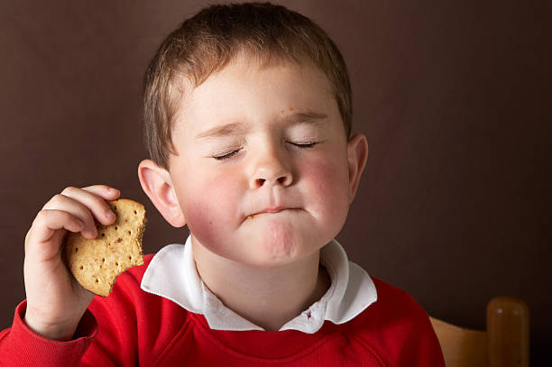 Four year old boy eating chocolate biscuit Four year old boy eating chocolate biscuit candy in mouth stock pictures, royalty-free photos & images