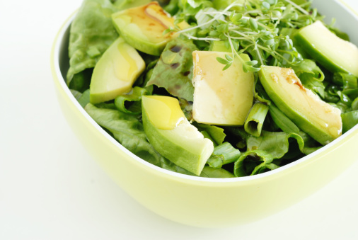 mixed green salad with avocado and cress in a bowl, with balsamic vinegar and olive oil
